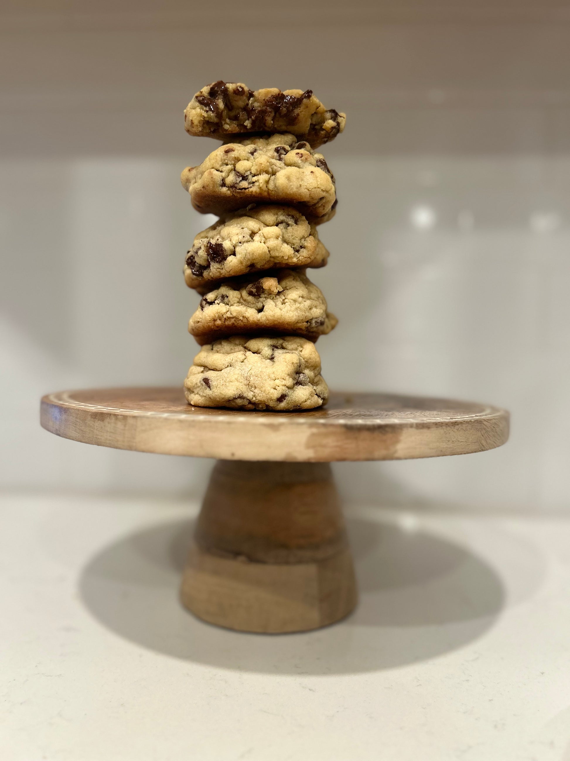 Stack of cookies on a wooden stand against a plain background